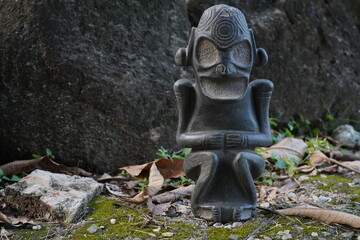Taino Antique Stone Cemi Idol Figure sitting on the ground on top of moss. Taino Indian Mythology.