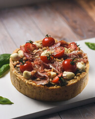 Soft focus.
Delicious cheesecake garnished with cherry tomatoes, bacon, parmesan, basil leaves on a light background.
European cuisine. Bakery products.