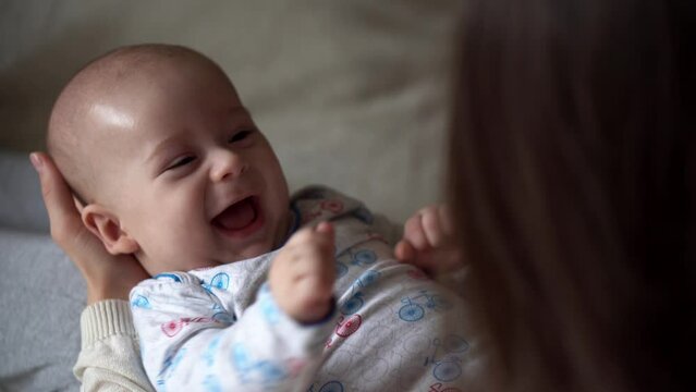 Newborn Baby With Young Mom look Into Each Other Eye. Cute Smiling Teethless Kid Face Portrait. Woman Kissing With Child Look At Camera. Infant, Mother Day, Childbirth, Beginning, Relationship Concept