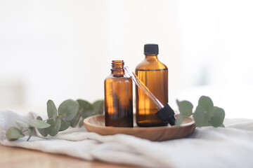 Essential oils in glass dark bottle. Skin and body care treatment concept. Eucalyptus branch.