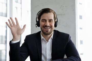 Webcam view businessman sit at workplace desk looks at camera wave hand greets client, start videoconference communication, take part in remote chat, use video call app. Virtual negotiations concept