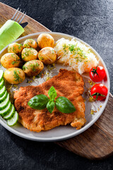 Pork cutlet coated with breadcrumbs with potatoes and cabbage
