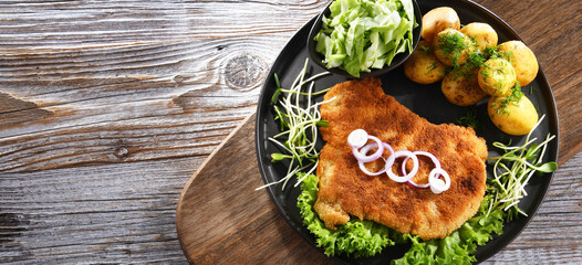 Pork cutlet coated with breadcrumbs with potatoes and cabbage - obrazy, fototapety, plakaty