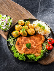 Pork cutlet coated with breadcrumbs with potatoes and cabbage