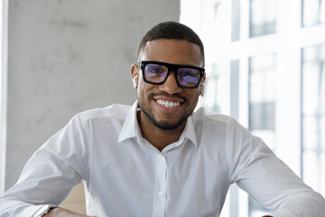Head shot portrait successful African businessman make videocall to client smile looks at cam wear...