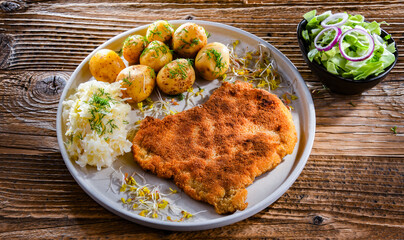 Pork cutlet coated with breadcrumbs with potatoes and cabbage