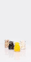 Vertical banner with a set of natural vitamin and supplement capsules in glass jars on light background with copy space. Card with immunity boosting pills and capsules. Biologically active additives