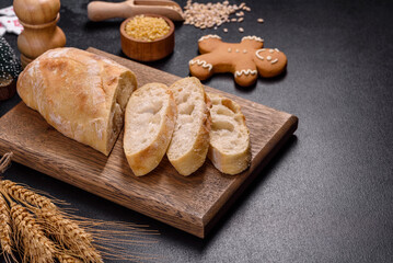 French baguette bread sliced on a wooden cutting board against a dark concrete background