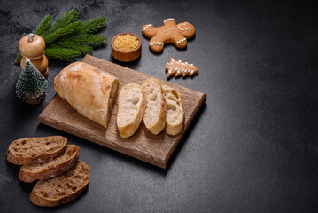 French baguette bread sliced on a wooden cutting board against a dark concrete background