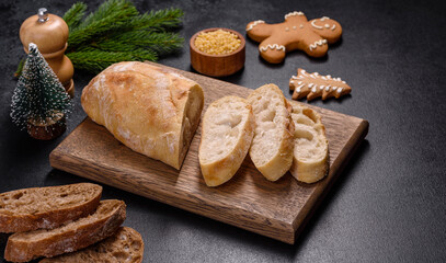 French baguette bread sliced on a wooden cutting board against a dark concrete background