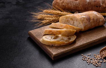 French baguette bread sliced on a wooden cutting board against a dark concrete background