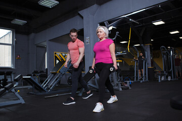 Fototapeta na wymiar Full length shot of a senior woman doing weighted lunges with personal trainer