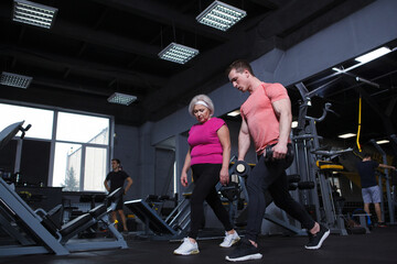 Fototapeta na wymiar Full length shot of a muscular personal trainer coaching elderly female client at the gym, copy space
