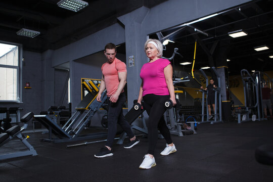 Full length shot of a senior woman doing weighted lunges with personal trainer