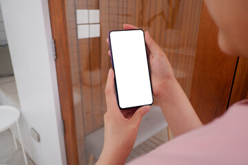 Mockup picture of business woman’s hands holding smart phone with white blank screen in modern place