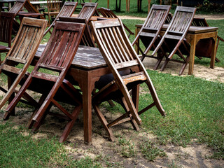 Empty old abandoned wooden dining table set on the green yard garden. Outdoor restaurant permanently closed with old dining table no use.