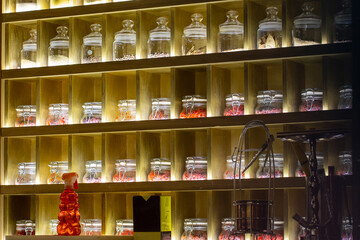 Tea and various spices in glass jars on shelves with lighting. Sale of tea in the store