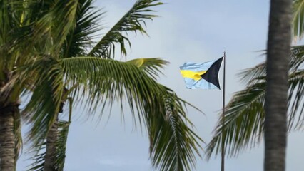 Bahamas flag blowing in the wind slow motion after recent tropical storm with ominous sky. 