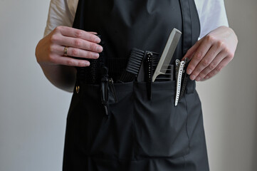 Close-up of scissors and combs in a holster box. Hairdressing tools inside a hairdresser's waist...