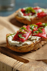 Crostini with marinated bell pepper strips on herb cream cheese. Close-up view.