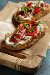 Crostini with marinated bell pepper strips on herb cream cheese. Close-up view.