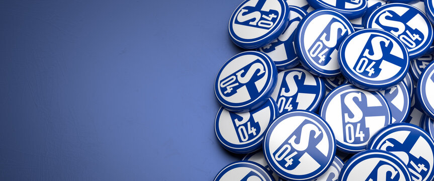 Logos of the German Soccer Club FC Schalke 04 on a heap on a table. Copy space. Web banner format