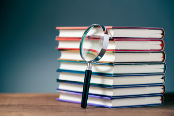 Magnifying glass and stack of hardcover books to research