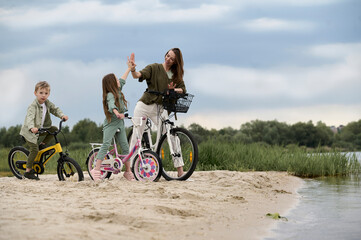 A cute family, a mother and her two children, give high five on the river band