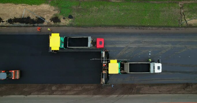 Laying new asphalt top view. Aerial view of road works, asphalt paver is laying a new layer of asphalt. Road construction equipment. Rollers rolling fresh hot asphalt on the new road. 
