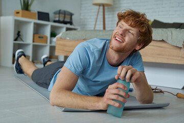 Handsome redhead man looking tired and happy after training at home