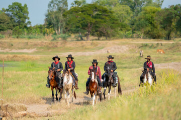 Group of cowboy on horse are riding to the village after finish take care of cow in background.