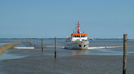 A passenger ferry from a Wadden Island approaches a harbor on the Wadden Sea