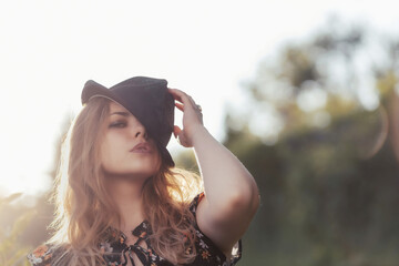 Summer portrait of posing attractive  young woman in black  straw hat in outside. Horizontally. 