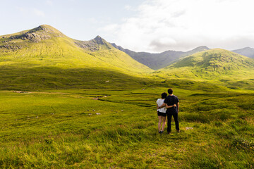 Fototapeta na wymiar Photo of a couple witnessing a landscape full of mountains on a summer day in the highlands, Scotland
