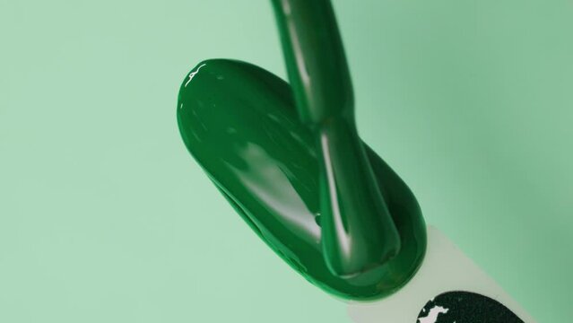applying green gel polish with a brush on an artificial nail tips