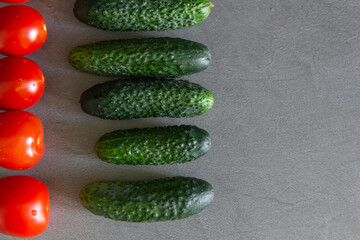 Fresh tomatoes and green cucumbers are laid out exactly in a row on the kitchen table. The cook is a perfectionist. Cook according to the recipe