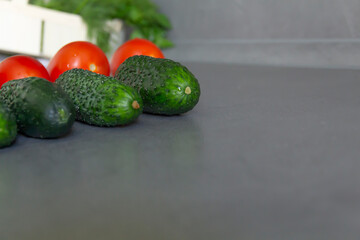 Fresh tomatoes and green cucumbers are laid out exactly in a row on the kitchen table. The cook is a perfectionist. Cook according to the recipe