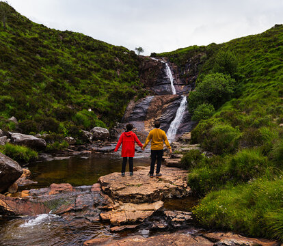 Photo of a couple seeing a small waterfall on a summer day in the isle of Skye, Scotland