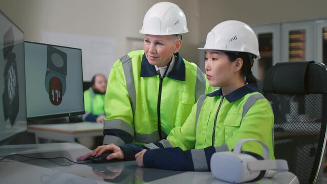 Portrait of project supervisor talking with a female industrial engineer point at computer screen
