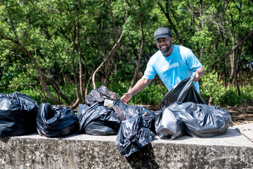 Volunteer picking up litter in the forest,volunteering, charity, people, ecology concept.volunteer...