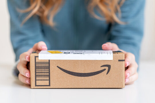 Woman holding in hands cardboard box delivered from Amazon
