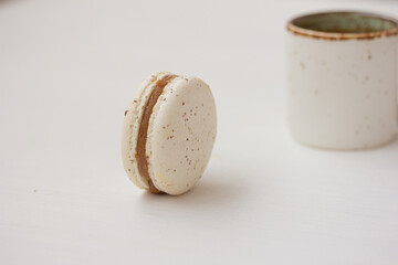 White macaron and a cup on white background. Salted caramel macaroon