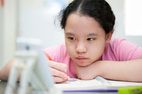 asia young girl learning online at home with wring book