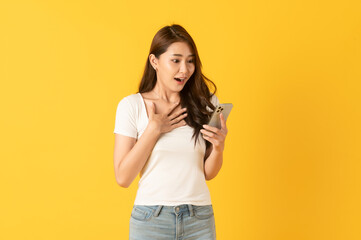 Surprise asian beautiful woman isolate on yellow background using smartphone