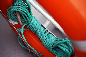 A green rope is wound and tied to a lifebuoy
