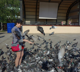 happy girl having fun feeding pigeons doves in a public urban square