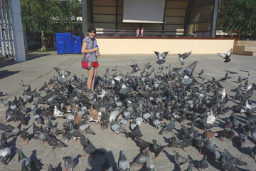 happy girl having fun feeding pigeons doves in a public urban square