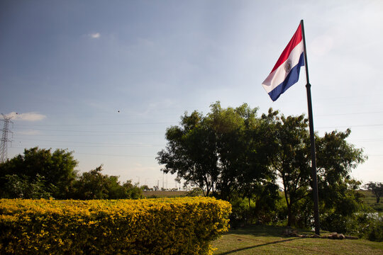 BANDERA DE PARAGUAY ONDEANDO EN LO ALTO DE UN ASTA EN EL PARQUE 
