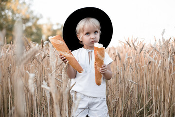 Beautiful portrait of a young child in a field. Children with bread. Little girl in cereal field. Happy baby girl on field of wheat with bread.