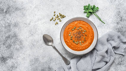 Pumpkin cream soup in a bowl on a gray concrete background. Vegetable soup puree. Clean organic...